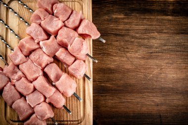 Pork kebab raw on skewers on a cutting board. On a wooden background. High quality photo