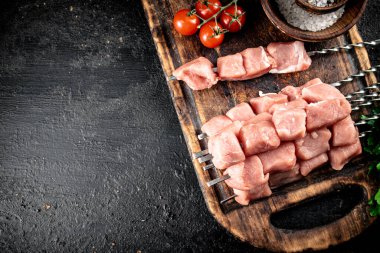 Fresh raw pork kebab on a cutting board. On a black background. High quality photo