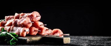 Fresh raw pork kebab on a cutting board. On a black background. High quality photo