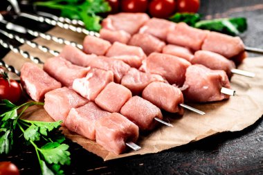 Pork kebab raw with parsley and cherry tomatoes. Against a dark background. High quality photo