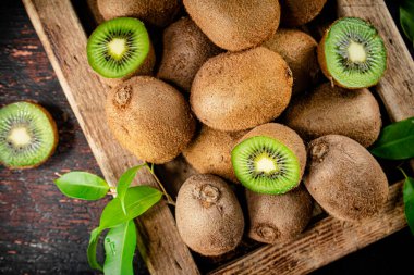 Fragrant kiwi with leaves on tray. On a rustic dark background. High quality photo