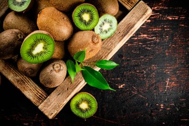 Fragrant kiwi with leaves on tray. On a rustic dark background. High quality photo