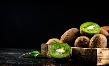 Fragrant kiwi with leaves on tray. On a rustic dark background. High quality photo
