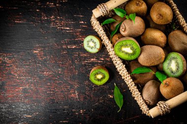 Fresh kiwi with leaves in a basket. On a rustic dark background. High quality photo