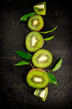 Pieces of kiwifruit with leaves. On a black background. High quality photo
