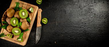 Kiwi in a basket on a wooden cutting board. On a black background. High quality photo