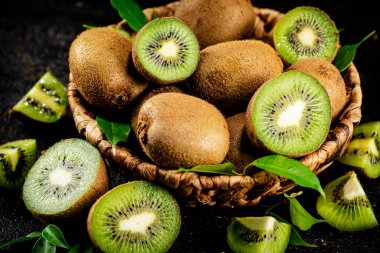 Fresh kiwi with leaves in a basket. On a black background. High quality photo