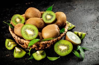 Fresh kiwi with leaves in a basket. On a black background. High quality photo