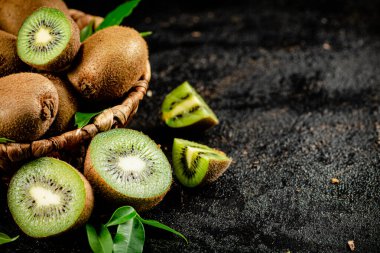 Fresh kiwi with leaves in a basket. On a black background. High quality photo