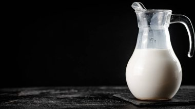 Milk in a jug on the table. On a black background. High quality photo