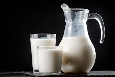 Fresh homemade milk on the table in a glass. On a black background. High quality photo