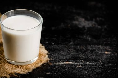 A full glass of fresh milk on a napkin. On a black background. High quality photo