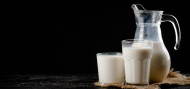 Fresh homemade milk on the table in a glass. On a black background. High quality photo
