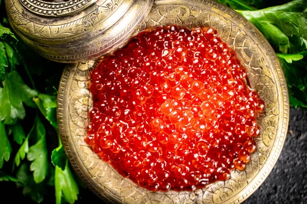 Full bowl of red caviar on the table. On a black background. High quality photo