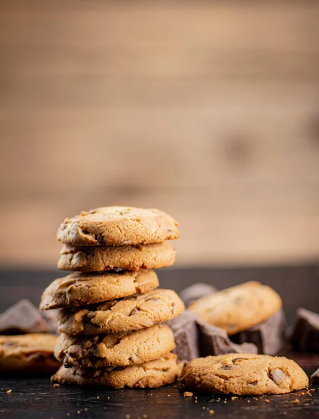 stock image Pile of homemade cookies with pieces of milk chocolate on the table. On a wooden background. High quality photo