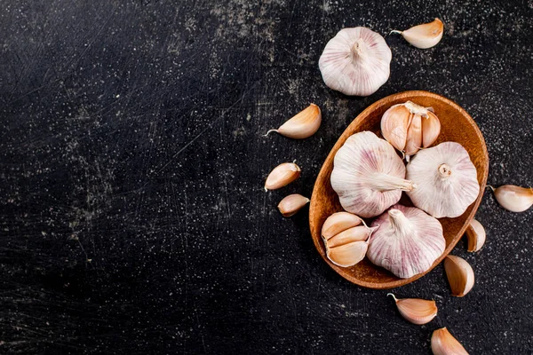 Fresh garlic on a wooden plate. On a black background. High quality photo