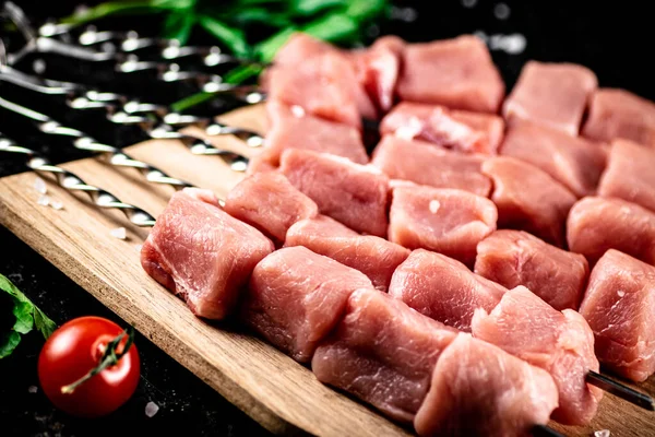 stock image Pork kebab raw on a cutting board with tomatoes and parsley. On a black background. High quality photo