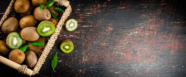 stock image Fresh kiwi with leaves in a basket. On a rustic dark background. High quality photo