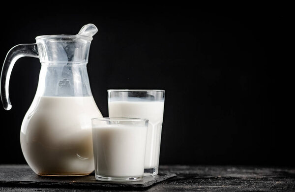 Milk in a jug on the table. On a black background. High quality photo