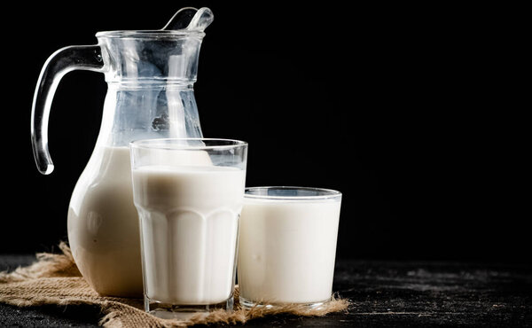 Fresh homemade milk on the table in a glass. On a black background. High quality photo
