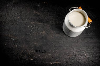 Fresh milk in a can on the table. On a black background. High quality photo