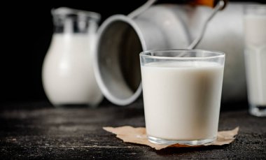 Fresh country milk in a glass on the table. On a black background. High quality photo