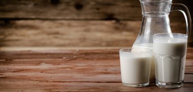 Milk in jugs and glasses. On a wooden background. High quality photo