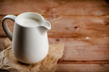 A jug of fresh milk on the table. On a wooden background. High quality photo