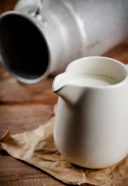 A jug of fresh milk on the table. On a wooden background. High quality photo