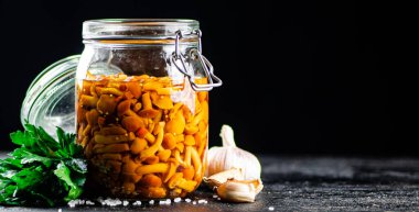 Fragrant pickled mushrooms in a glass jar. On a black background. High quality photo