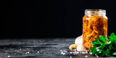 Marinated mushrooms with a glass jar with parsley and garlic. On a black background. High quality photo