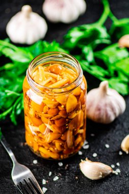 Marinated mushrooms with a glass jar with parsley and garlic. On a black background. High quality photo