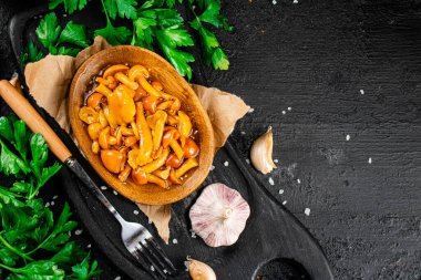 Marinated mushrooms on a plate with parsley. On a black background. High quality photo