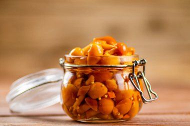 Glass jar with marinated mushrooms. On a wooden background. High quality photo