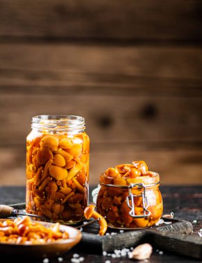 Jar with marinated mushrooms on the table. On a wooden background. High quality photo