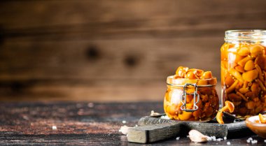 Jar with marinated mushrooms on the table. On a wooden background. High quality photo