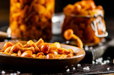 Delicious marinated mushrooms in a jar and on a plate. Against a dark background. High quality photo