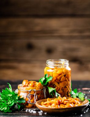 Jar with marinated mushrooms on the table. On a wooden background. High quality photo