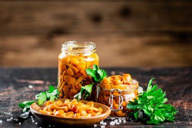 Jar with marinated mushrooms on the table. On a wooden background. High quality photo