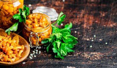 Delicious marinated mushrooms in a jar and on a plate. Against a dark background. High quality photo