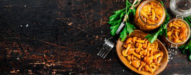 Delicious marinated mushrooms in a jar and on a plate. Against a dark background. High quality photo