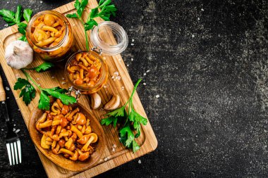 Marinated mushrooms with parsley on a wooden cutting board. On a black background. High quality photo