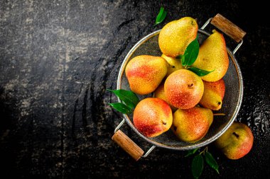 Juicy pears in a colander with foliage. On a black background. High quality photo