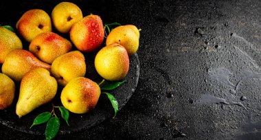 Ripe pears with leaves on a stone board. On a black background. High quality photo