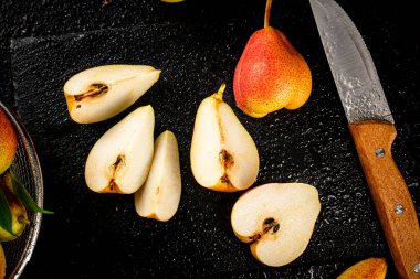 Sliced ripe pear with a knife. On a black background. High quality photo