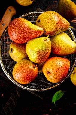 Ripe pears in a colander. On a rustic dark background. High quality photo