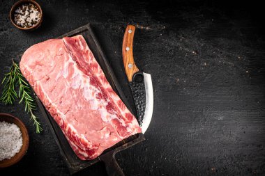 Raw pork on a cutting board with spices and a knife. On a black background. High quality photo