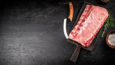 Raw pork on a cutting board with spices and a knife. On a black background. High quality photo