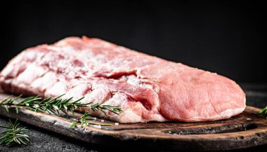 Fresh raw pork on a cutting board with rosemary. On a black background. High quality photo