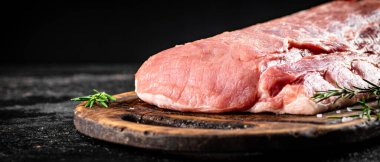 Fresh raw pork on a cutting board with rosemary. On a black background. High quality photo